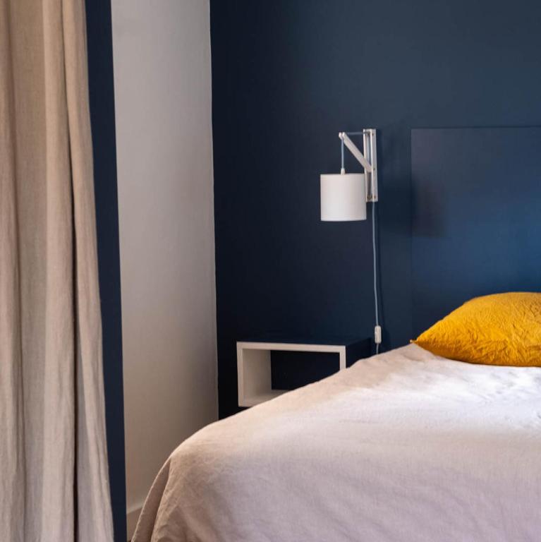 une chambre avec un mur bleu et un lit avec un oreiller jaune dans l'établissement Maison Cimes, aux Orres