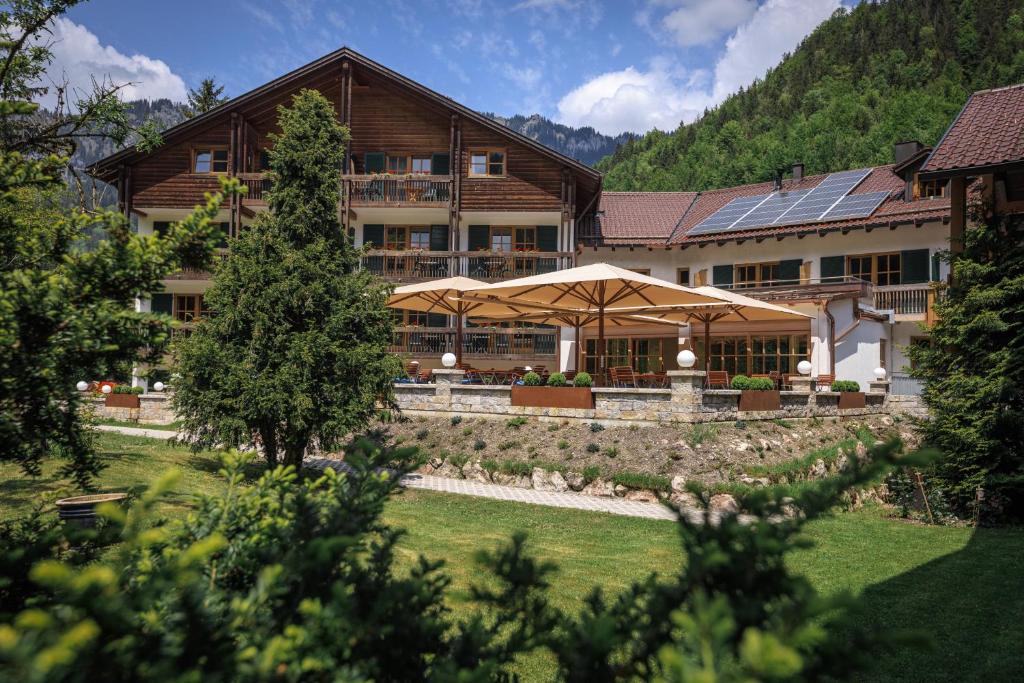 un grande edificio con ombrelloni di fronte di Alphotel Ettal a Ettal