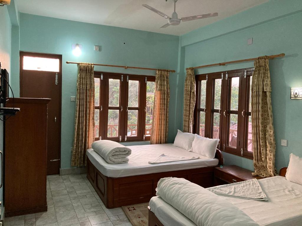 1 dormitorio con 2 camas y 2 ventanas en Sauraha Guest House, en Sauraha