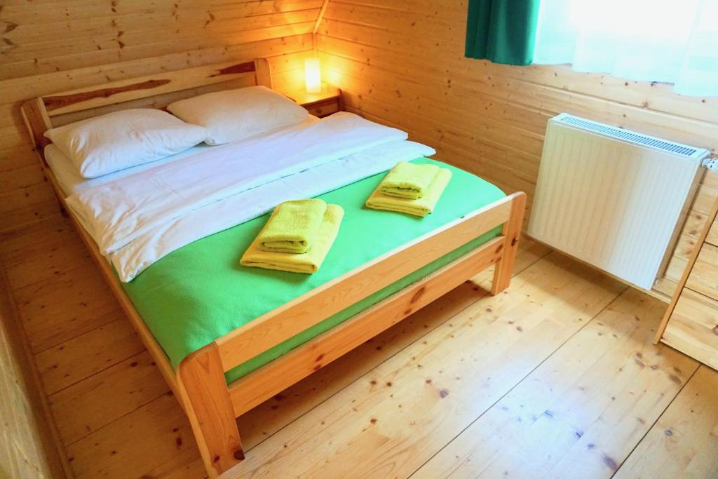 a bed in a wooden room with two towels on it at Zielone Domki in Pobierowo
