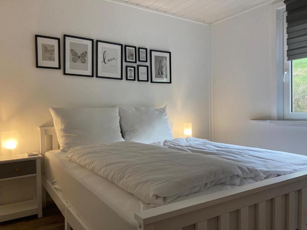 a white bed in a bedroom with pictures on the wall at Familienchalets am Millstätter See in Rothenthurn