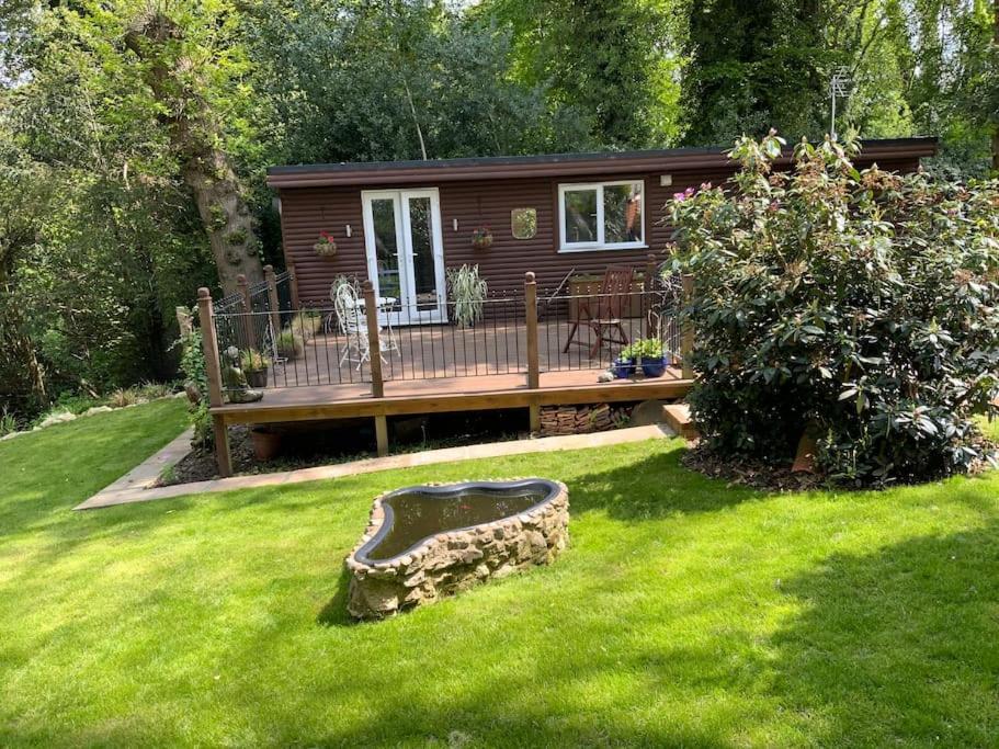 Cabaña pequeña en un patio con terraza de madera en Eve’s Contemporary Cabin in Kent Woodland Setting, en Kent