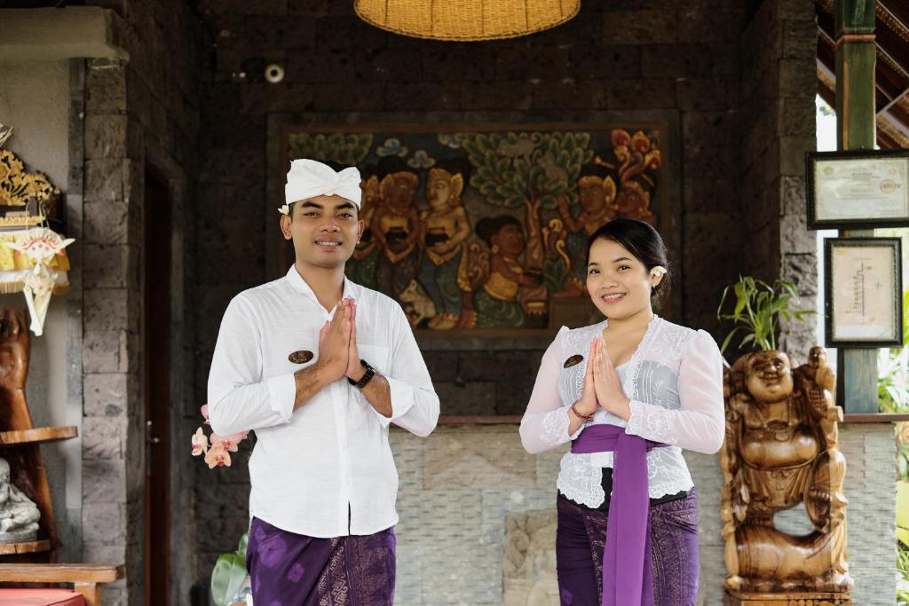 un uomo e una donna pregano davanti a un edificio di Teja Lokha Ubud Villa ad Ubud