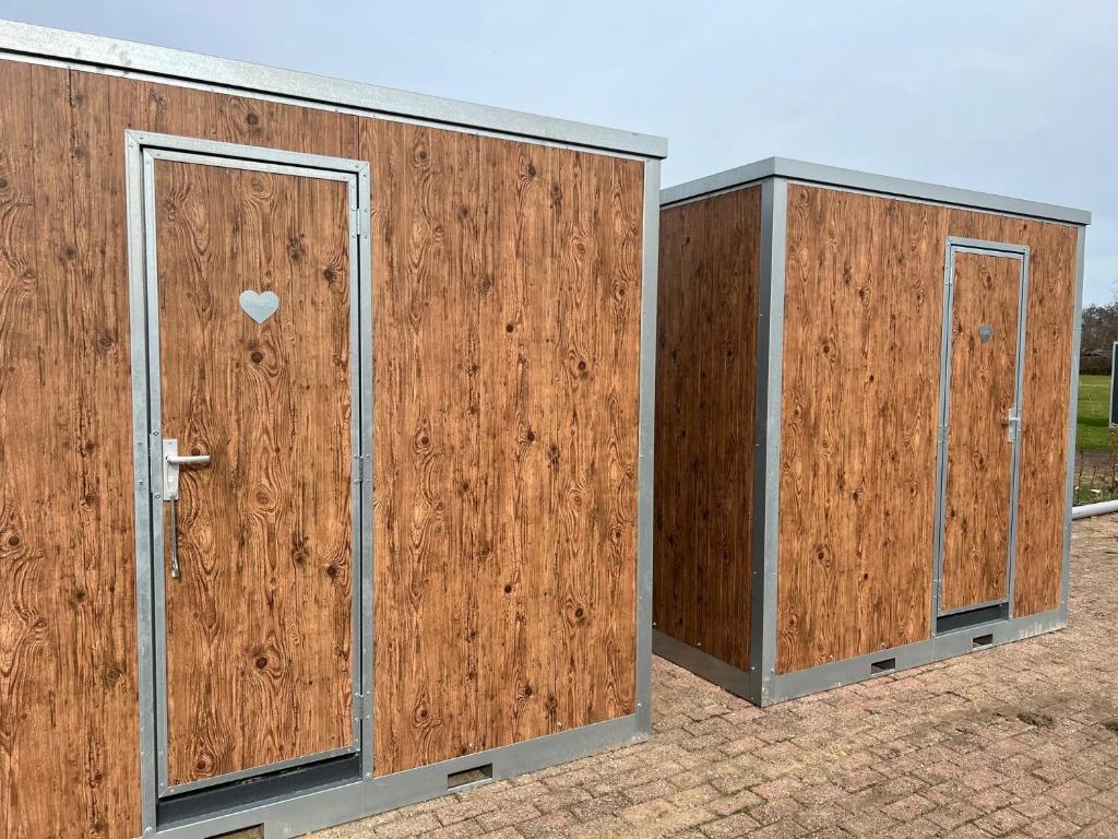 ein Paar Holzgebäude mit einer Tür in der Unterkunft Hoogte Huisje Fantasie in Swalmen