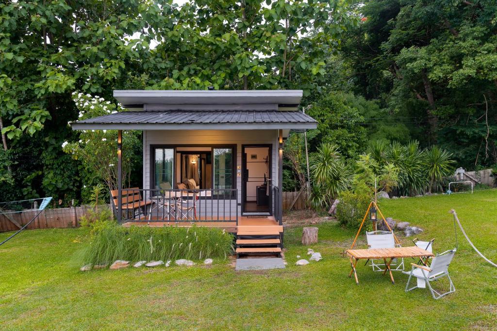 ein kleines Haus in einem Garten mit einer Veranda in der Unterkunft Naramountainkhaoyai 04 in Ban Tha Chang