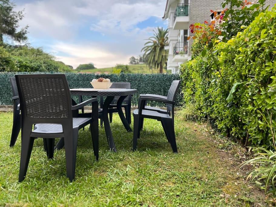 dwa krzesła i stół w trawie w obiekcie Casa adosada en Argoños w mieście Argoños