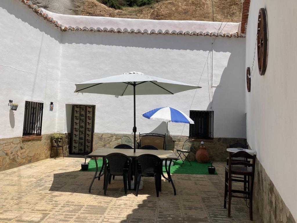 einen Tisch und Stühle mit Sonnenschirm auf einer Terrasse in der Unterkunft Casa Cueva Rural Estación de Guadix in Guadix