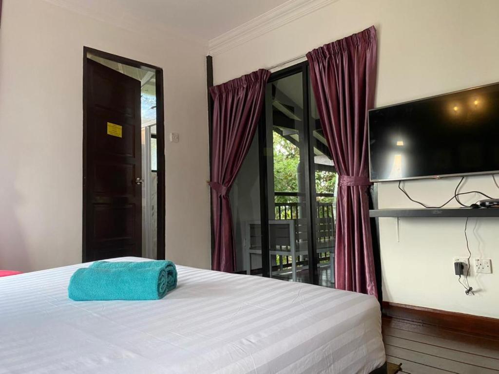 ein Schlafzimmer mit einem Bett und einem blauen Handtuch darauf in der Unterkunft THE HIGHLANDS VILLA in Tanah Rata