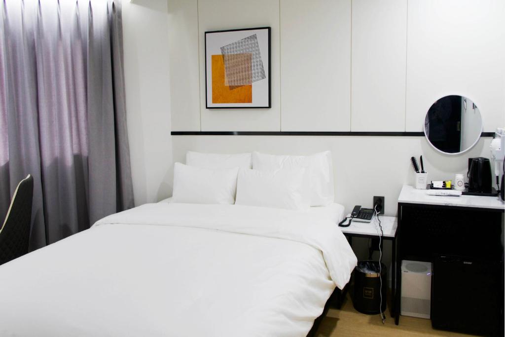 a bedroom with a white bed and a desk at Number 25 Hotel Jecheon in Jecheon
