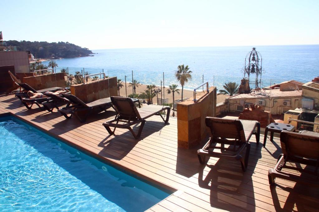 eine Terrasse mit Stühlen und einen Pool am Meer in der Unterkunft Hotel Metropol in Lloret de Mar
