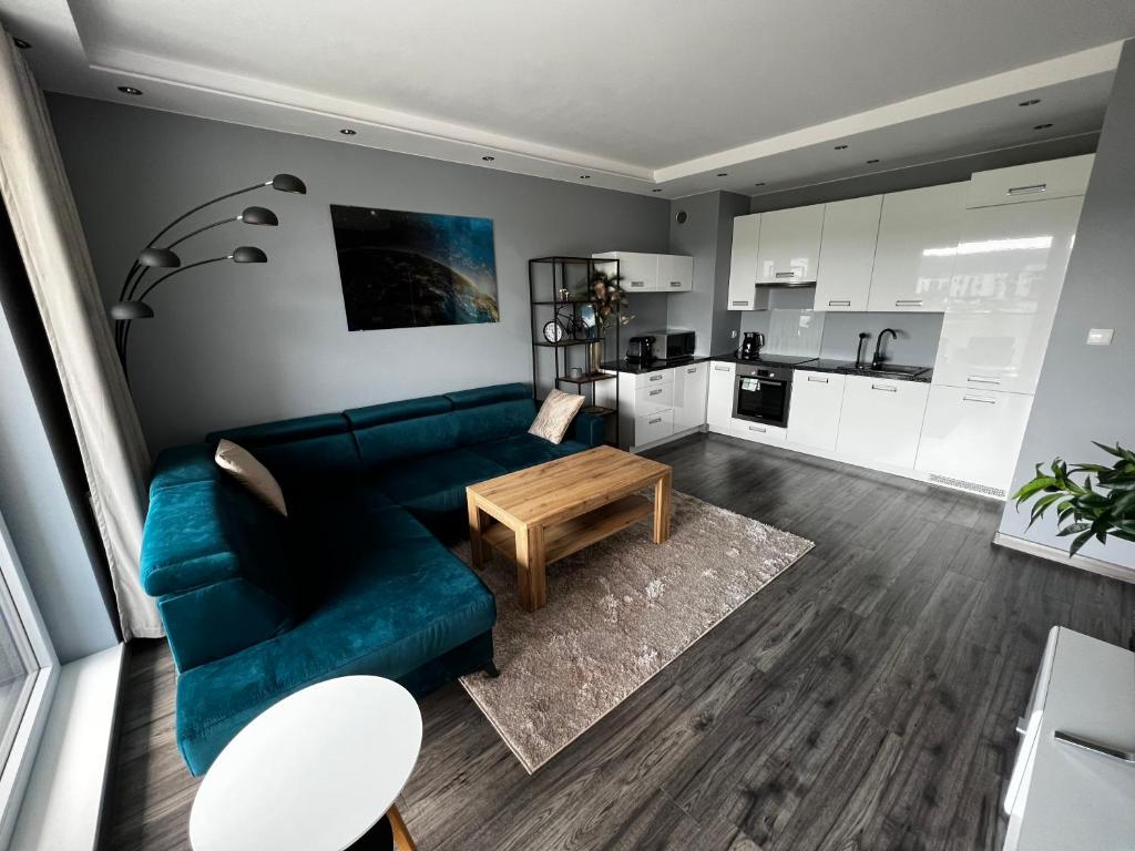 a living room with a blue couch and a coffee table at Przytulny apartament do wynajęcia in Reda