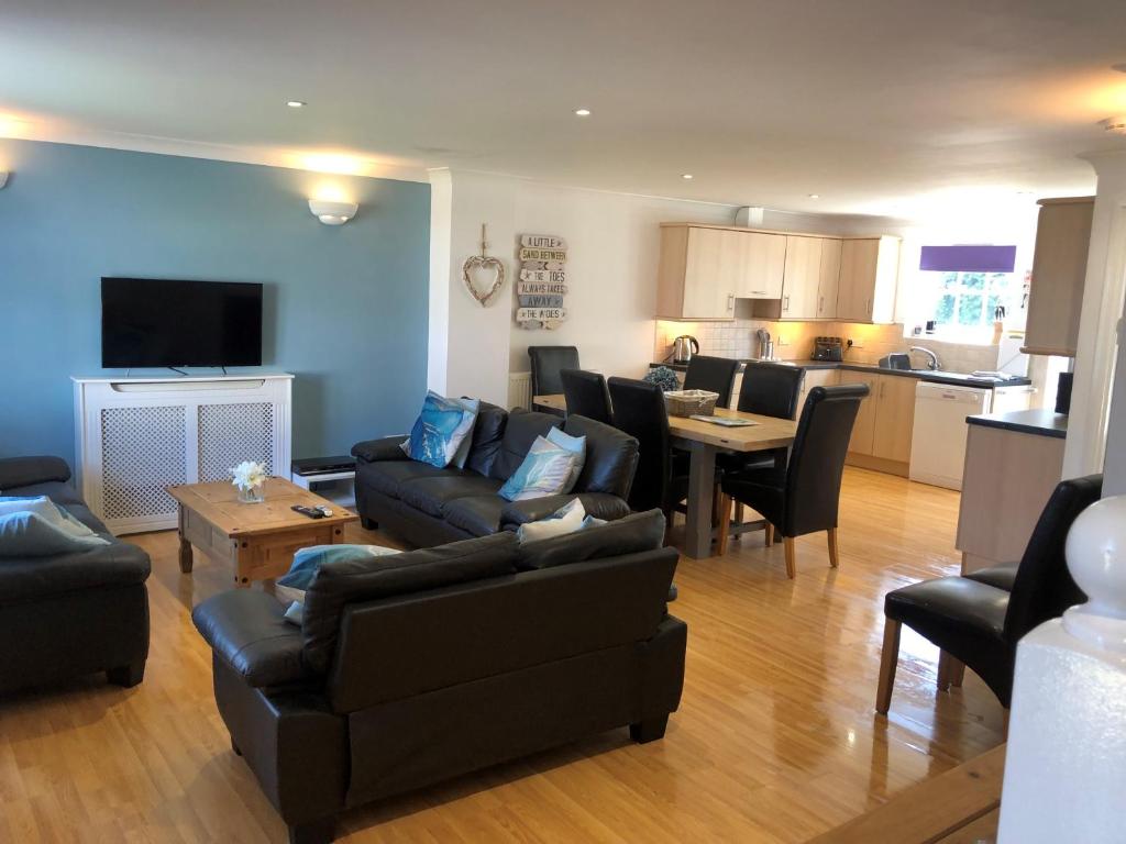 a living room with a couch and chairs and a kitchen at Waves in Saint Columb Major