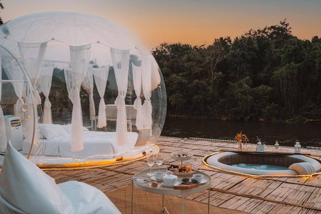 une terrasse avec une tente à bulles et un bain à remous. dans l'établissement The Three Bubble Houses, à Sai Yok
