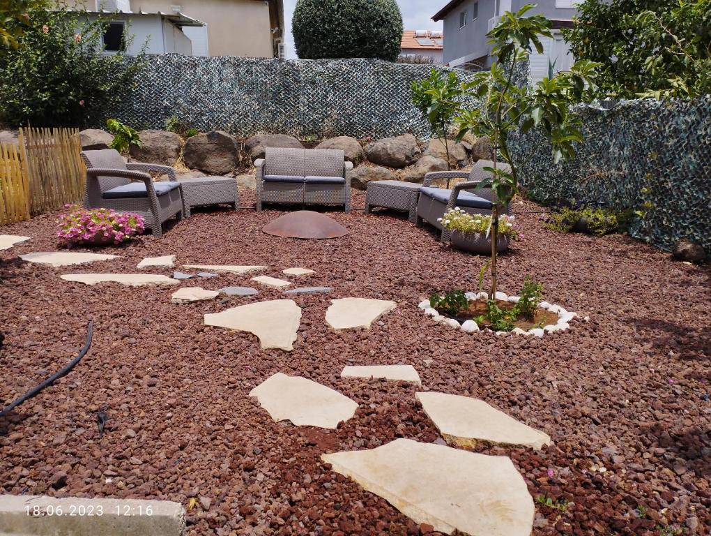 un jardín con sillas, un árbol y rocas en Limor-resident, en Katzrin