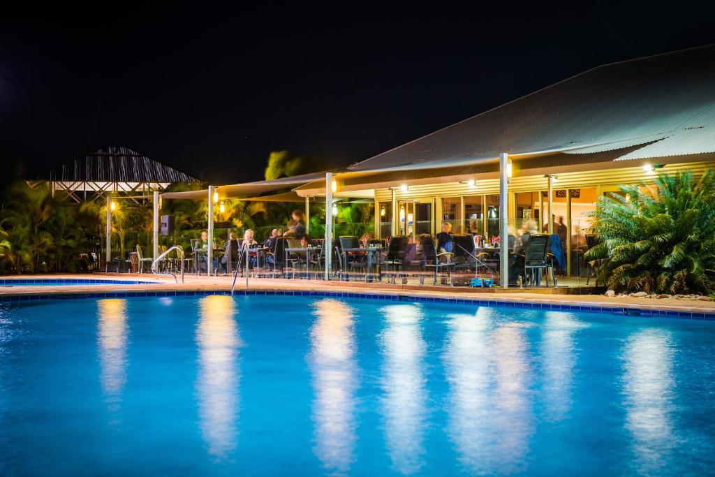 a swimming pool in front of a restaurant at night at Exmouth Escape Resort in Exmouth