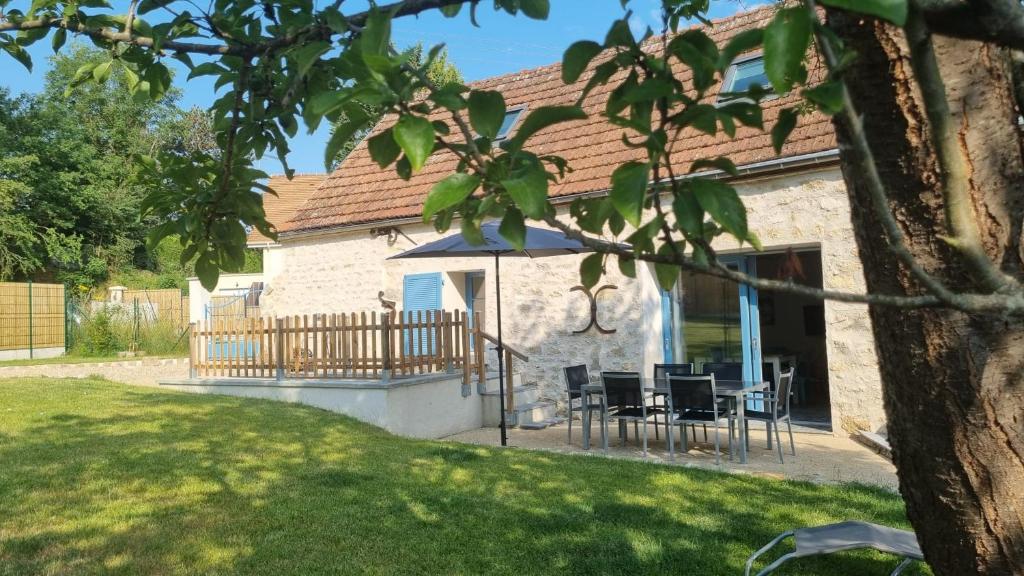 Cette maison dispose d'une terrasse avec des chaises et un parasol. dans l'établissement La Grange, à Seraincourt