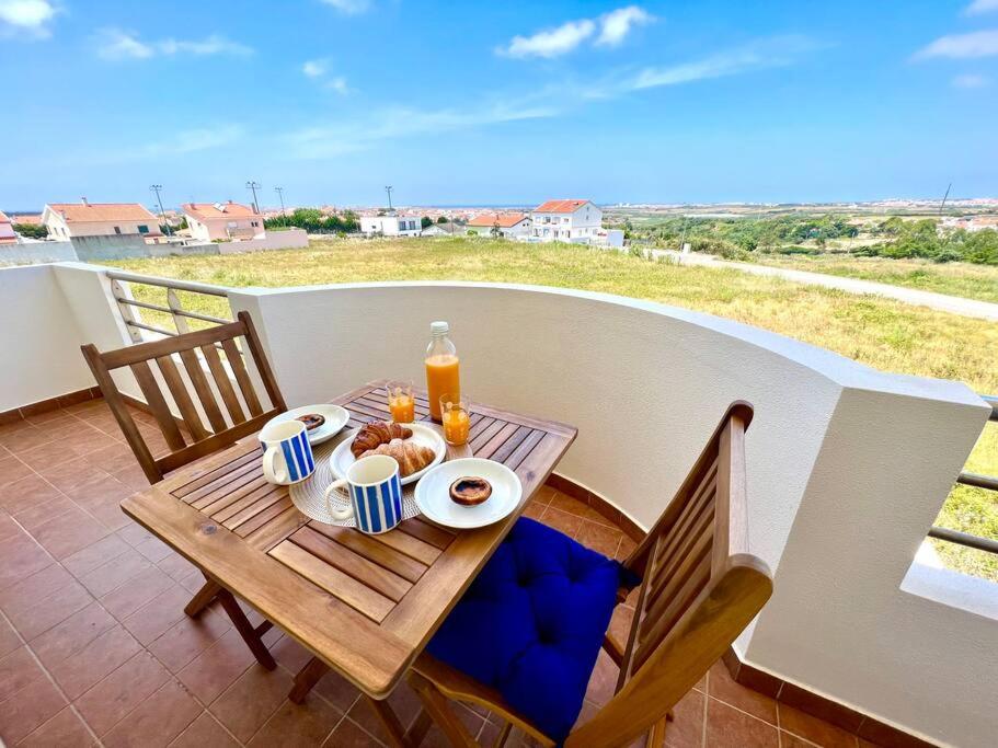uma mesa com comida e bebidas numa varanda em Appartement T2 avec vue panoramique sur la côte em Atouguia da Baleia