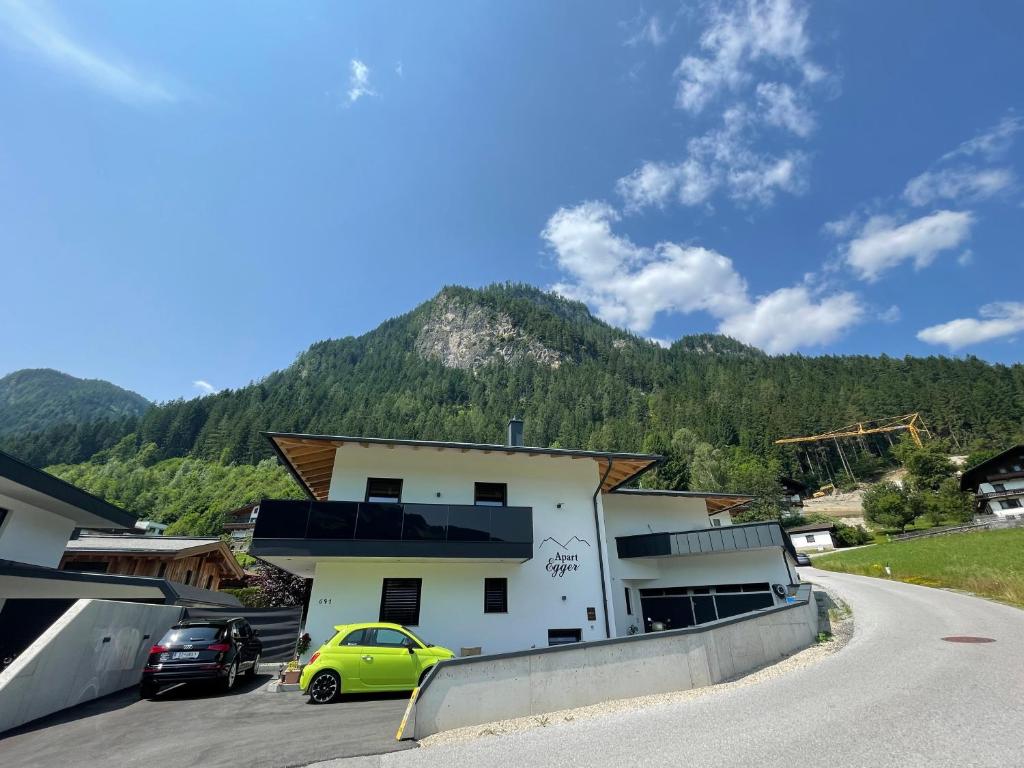 a building with a yellow car parked in a parking lot at Apart Egger in Schwendau