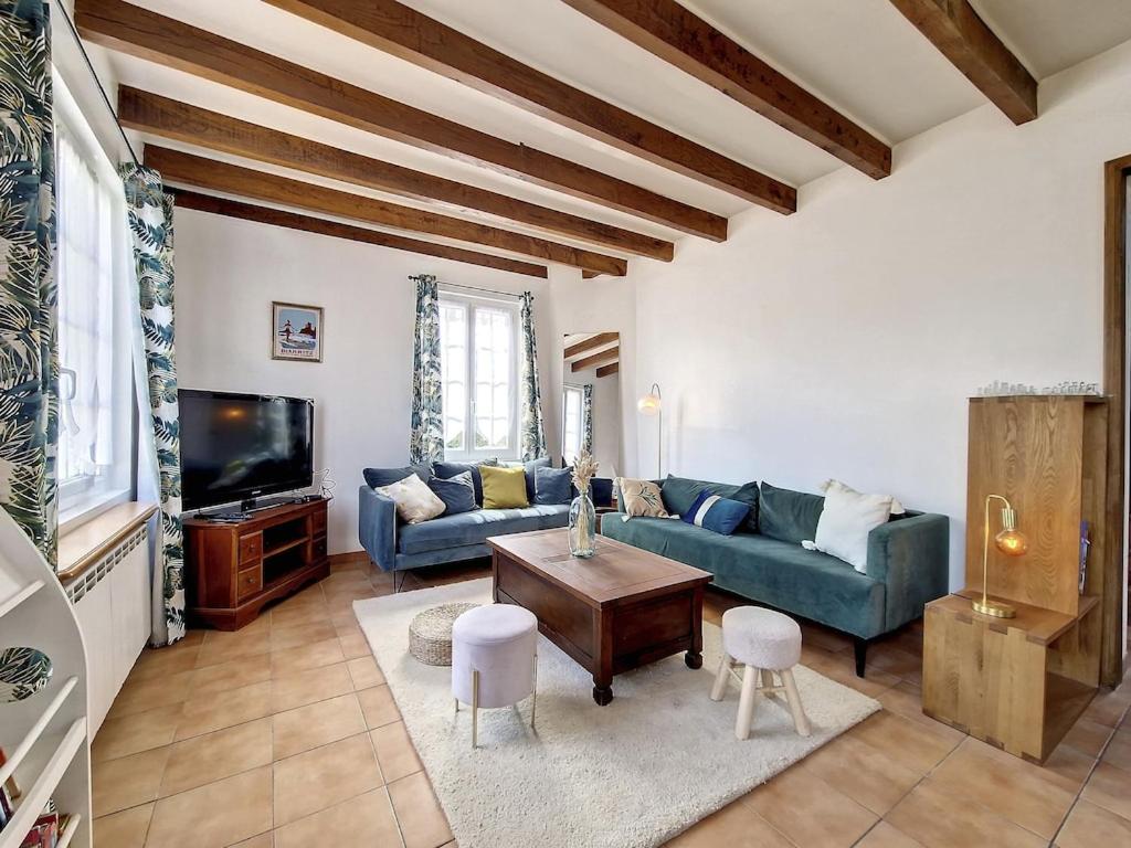 sala de estar con sofá azul y TV en Maison au coeur d’Arcangues, proximité de Biarritz, en Arcangues
