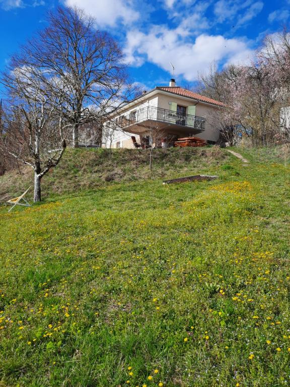 una casa in cima a una collina con un campo di fiori di Les coteaux de Planèze, maison et jardin dans le Lot! Chambres chez l'habitant! a Belmont-Bretenoux