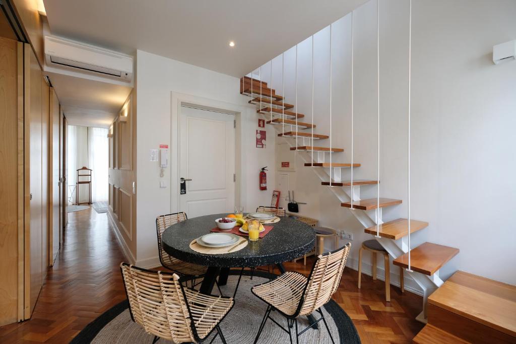 Impar Luxury Apartments في بورتو: غرفة طعام مع طاولة وكراسي ودرج
