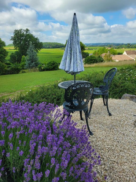 un parapluie posé à côté d'une table et des fleurs violettes dans l'établissement Chez Turnbulls, à Pomport