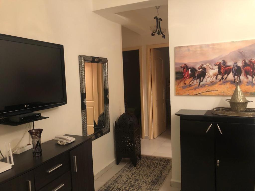 a living room with a television and a painting of horses at Sublime Appartement Marjane in Marrakech