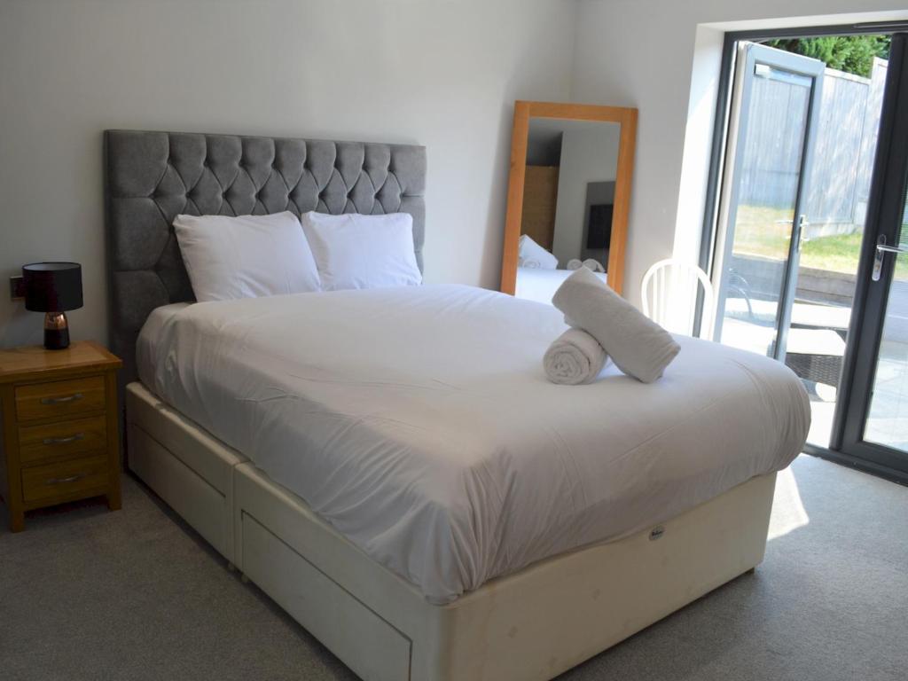 a bedroom with a large white bed with a headboard at Pass the Keys Spacious modern lovely bungalow in Bournemouth