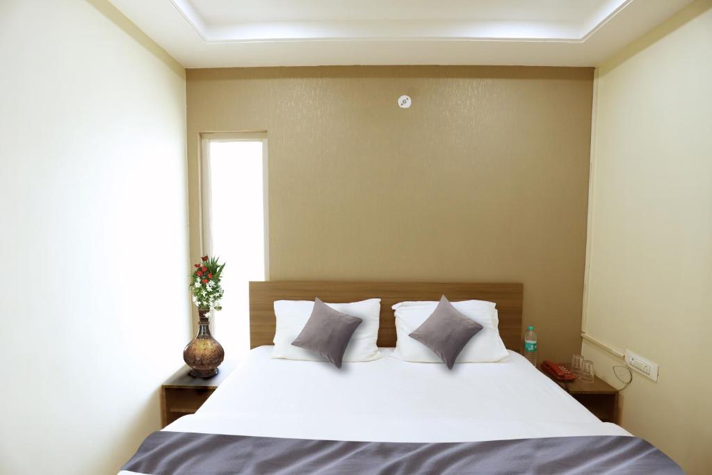 a bedroom with a bed with white sheets and pillows at Heaven Hotel in Bareilly