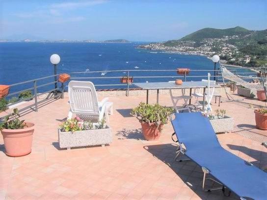 伊斯基亞的住宿－Appartamenti Miramare in Collina，一个带桌椅的庭院和大海