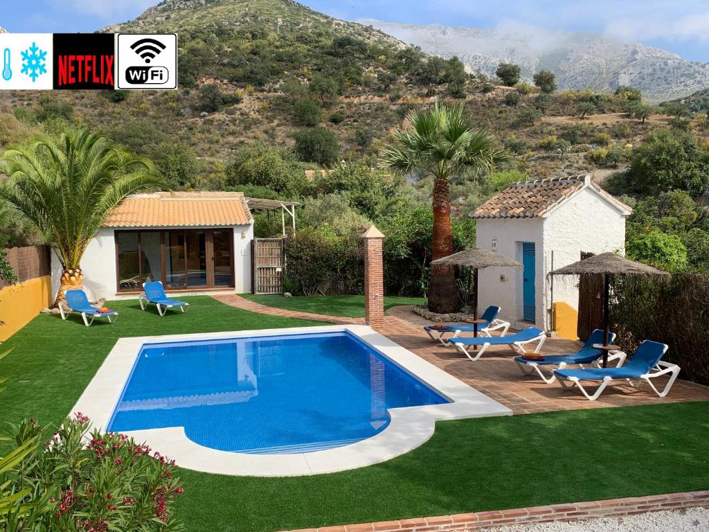 uma piscina num quintal com cadeiras e uma casa em Casa Rural La teja (Caminito del Rey) em El Chorro