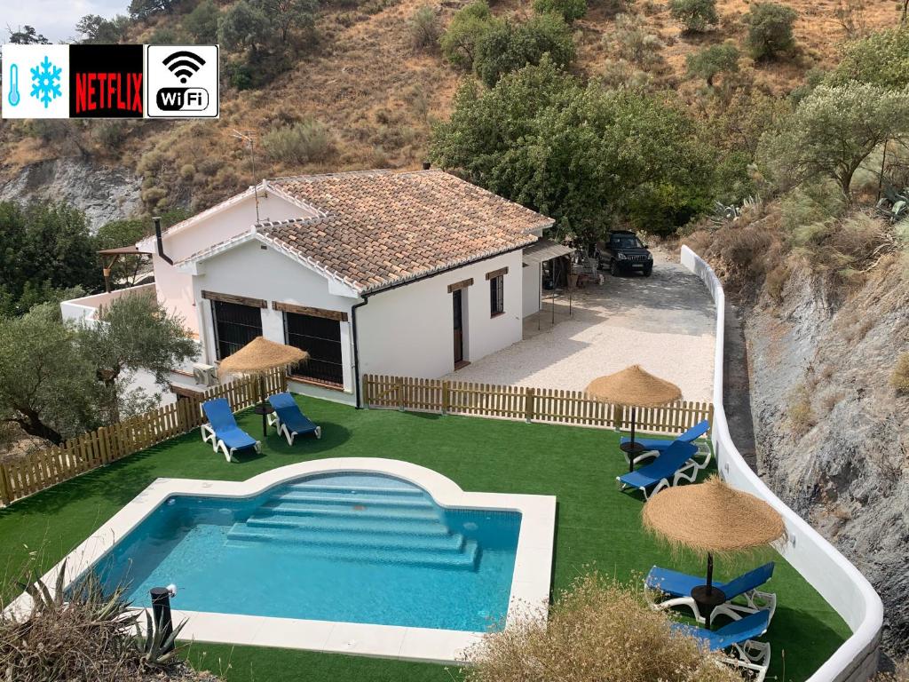 a villa with a swimming pool in front of a house at Casa Rural Las Angosturas (Caminito del Rey) in El Chorro