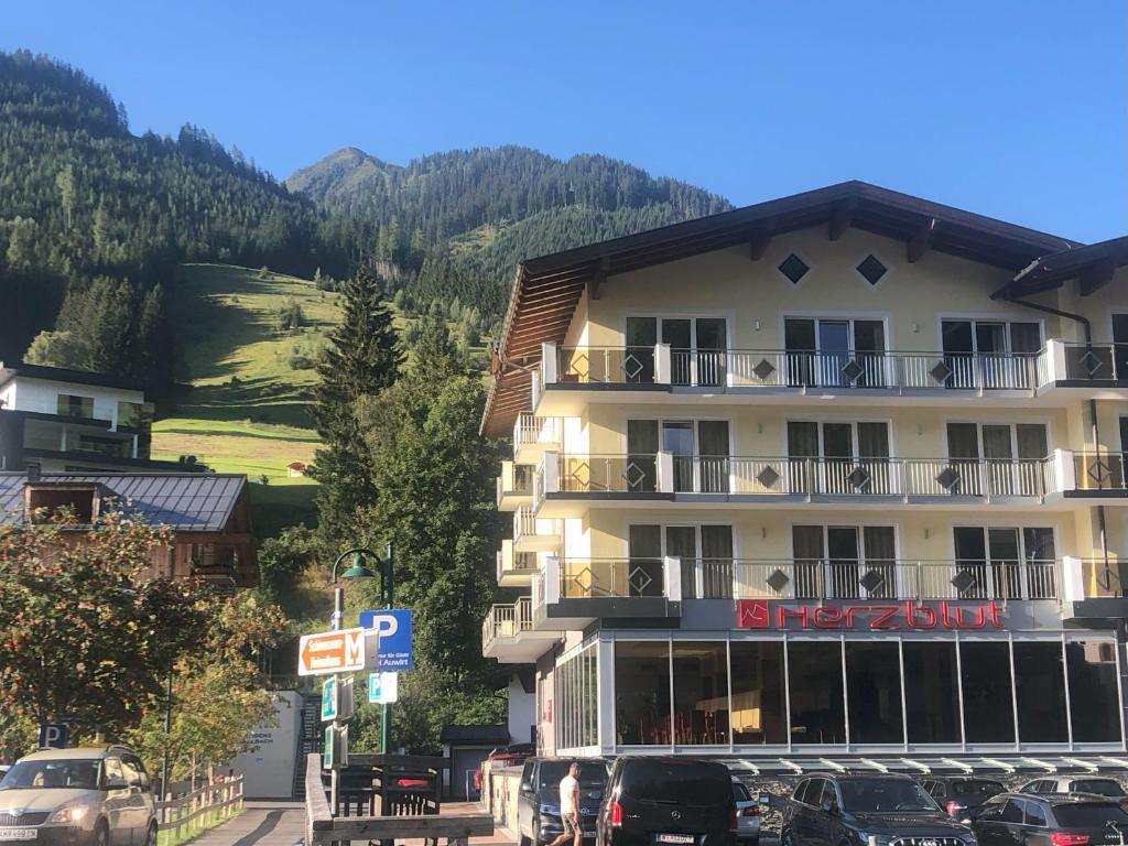 un grande edificio con macchine parcheggiate di fronte di Hotel Herzblut - Joker card included in summer a Saalbach Hinterglemm