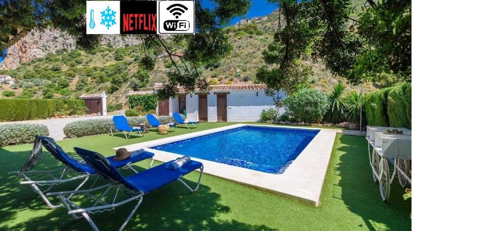 a swimming pool in a yard with chairs and a house at Alojamiento Rural Caminito del Rey in El Chorro