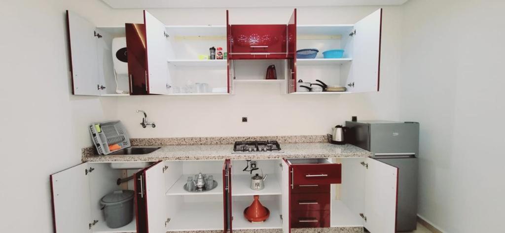 een kleine keuken met witte kasten en rode apparaten bij Agadir chez Omar in Agadir