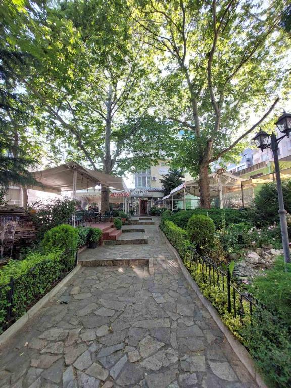 a garden with a stone walkway with trees and benches at Apartments near to Burgas Free University in Burgas