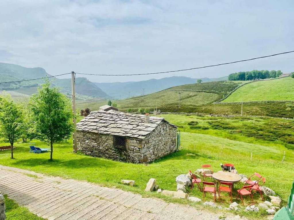 una casa de piedra con mesa y sillas en un campo en Refugio Castro Valnera, en Espinosa de los Monteros