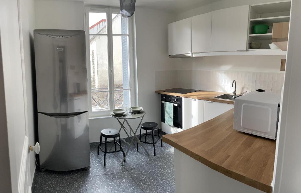 una cocina con nevera y 2 taburetes. en Charmant studio proche RER B direction Paris, en Fontenay-aux-Roses