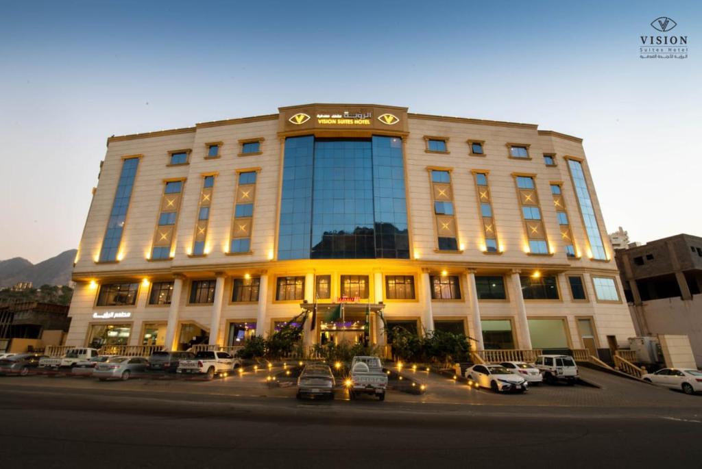 un grande edificio con macchine parcheggiate di fronte di فندق الرؤية محافظة الداير بني مالك a Al Buhrah