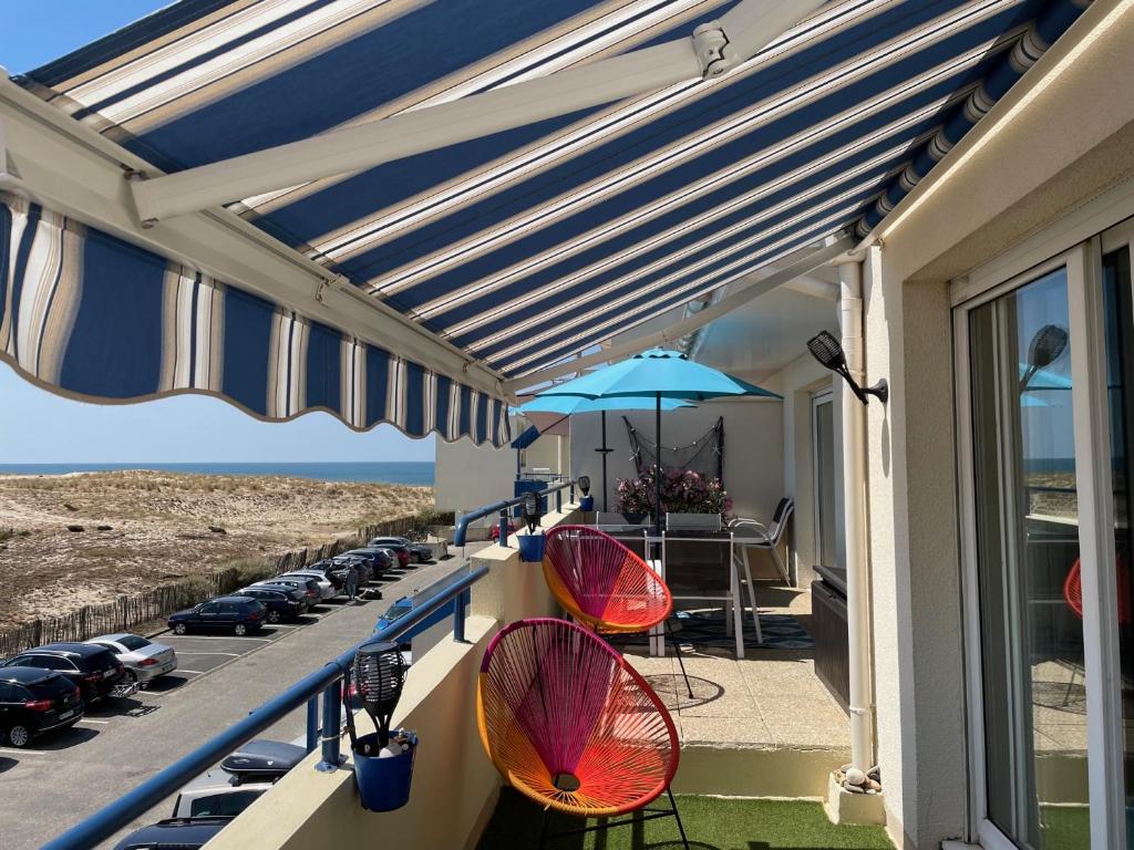 balkon z 2 parasolami, stołem i krzesłami w obiekcie T3 FRONT DE MER LACANAU OCEAN - 22m2 TERRASSE -2 PISCINES -WIFI-PARKING w mieście Lacanau-Océan