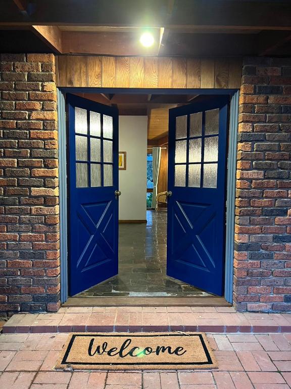 a brick building with blue doors and a welcome mat at Wandjoo Cottage Cranbourne in Lyndhurst South