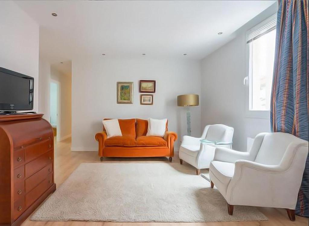 sala de estar con sofá naranja y 2 sillas blancas en COSY Apartment AREETA STATION las Arenas Getxo, en Getxo