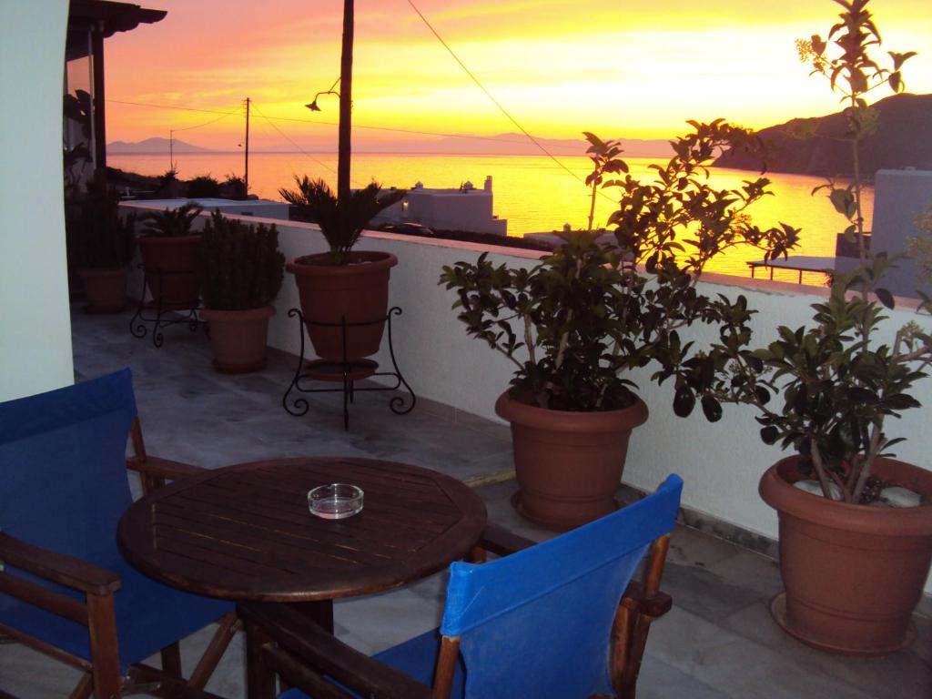 uma mesa e cadeiras numa varanda com um pôr-do-sol em Pelagos em Aegiali