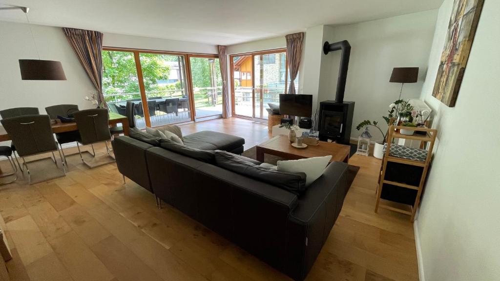 a living room with a black couch and a table at Wunderschöne Wohnung am See mit Sauna & Whirlpool in Unterterzen