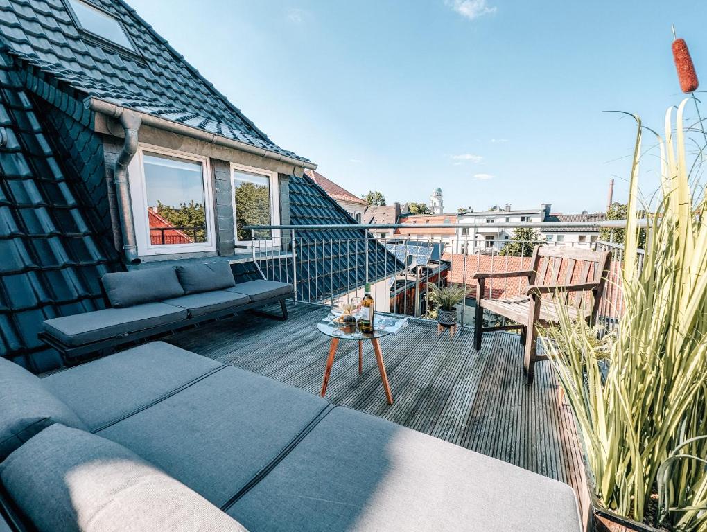patio con sofá y mesa en el balcón en 4-Schlafzimmer-Terrassensuite Oasis - WORKSPACE EM-APARTMENTS DEUTSCHLAND, en Bielefeld