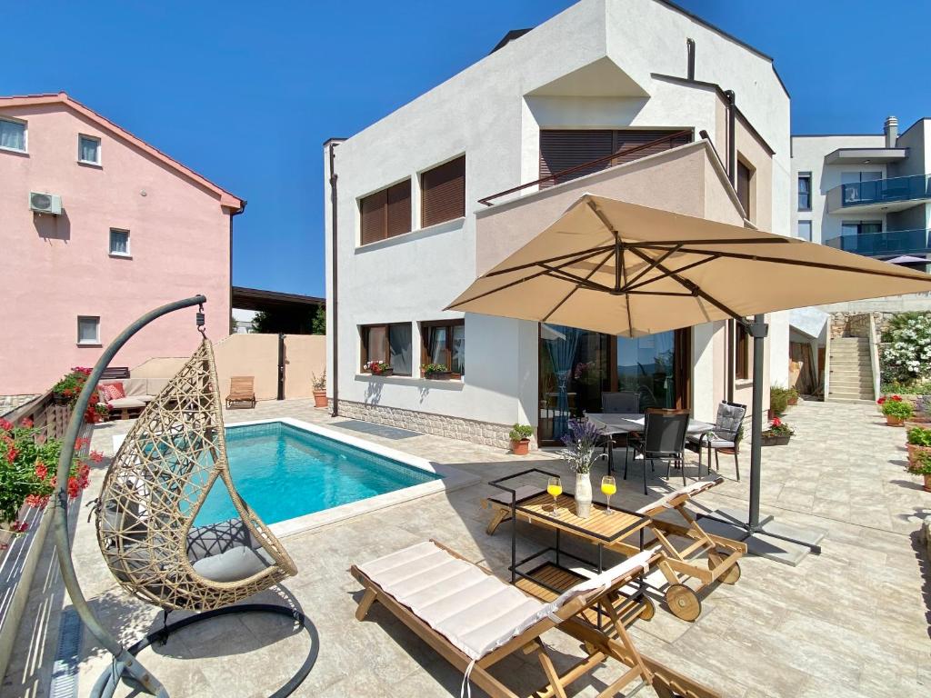 a patio with a swing and an umbrella next to a pool at Charming Villa Ira with Pool in Krk