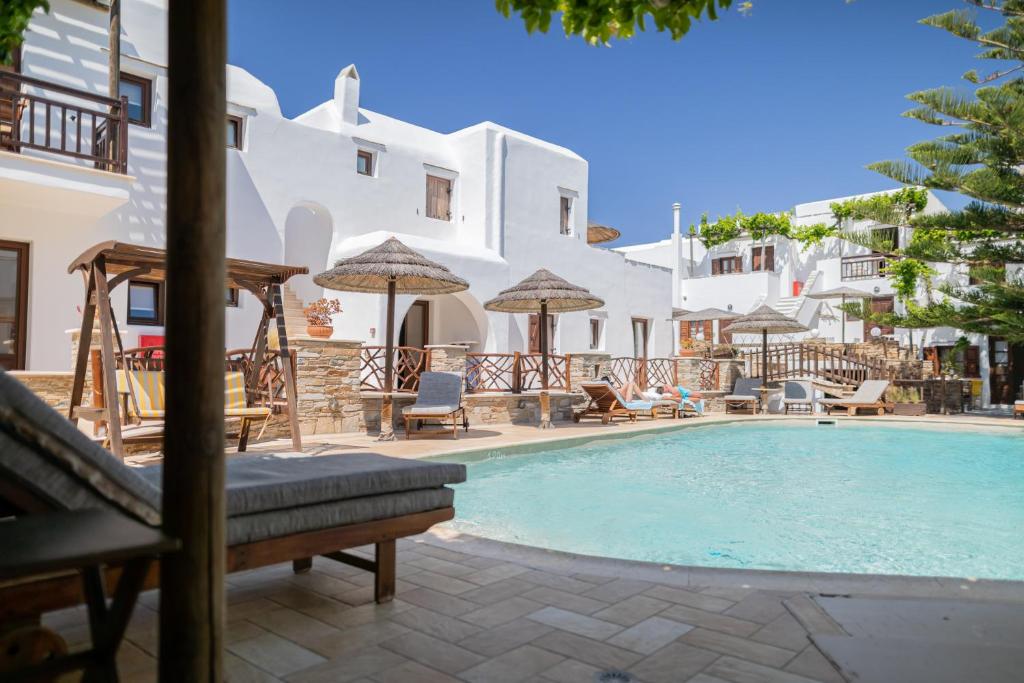 uma piscina com cadeiras e guarda-sóis ao lado de um edifício em Anemomilos em Agia Anna Naxos