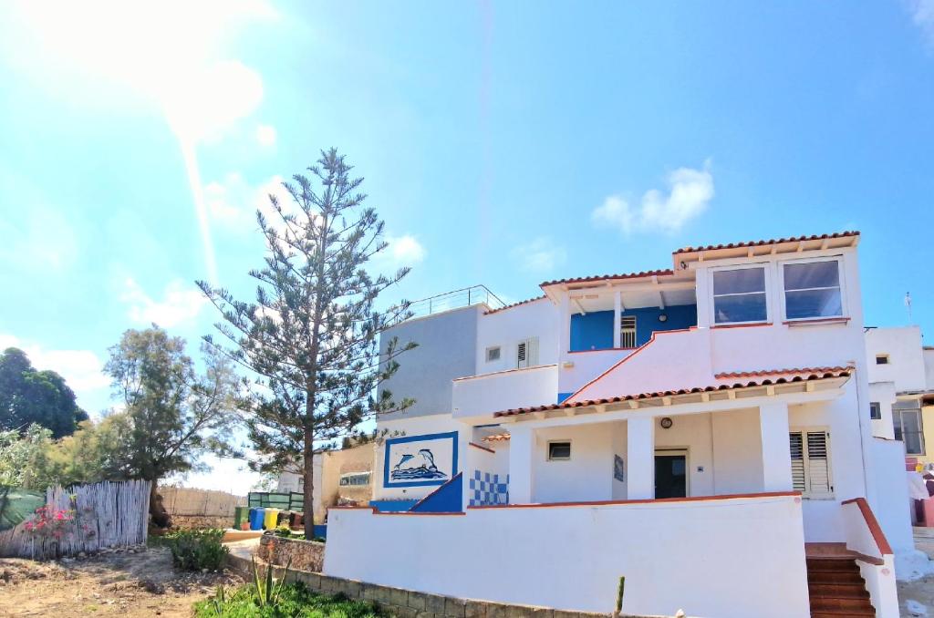 una casa bianca con un albero davanti di Case Pescatori a Lampedusa