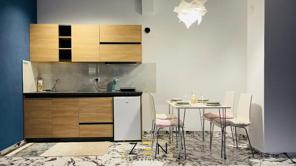 a kitchen with a sink and a table with chairs at Zen Apartments Pejë in Peje