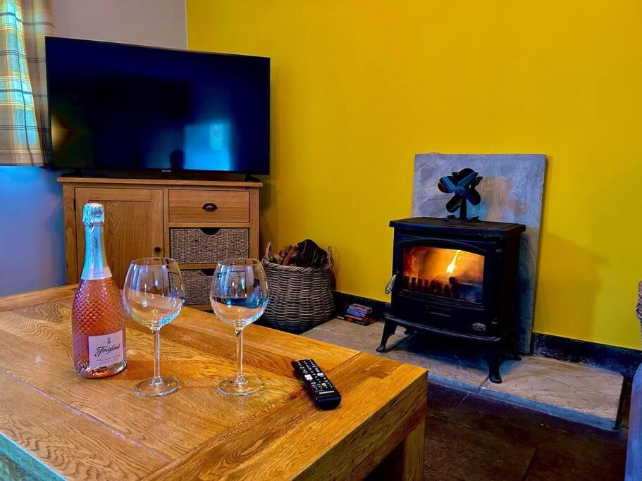 un soggiorno con 2 bicchieri da vino e un camino di Lluest a Llanddewi-Brefi